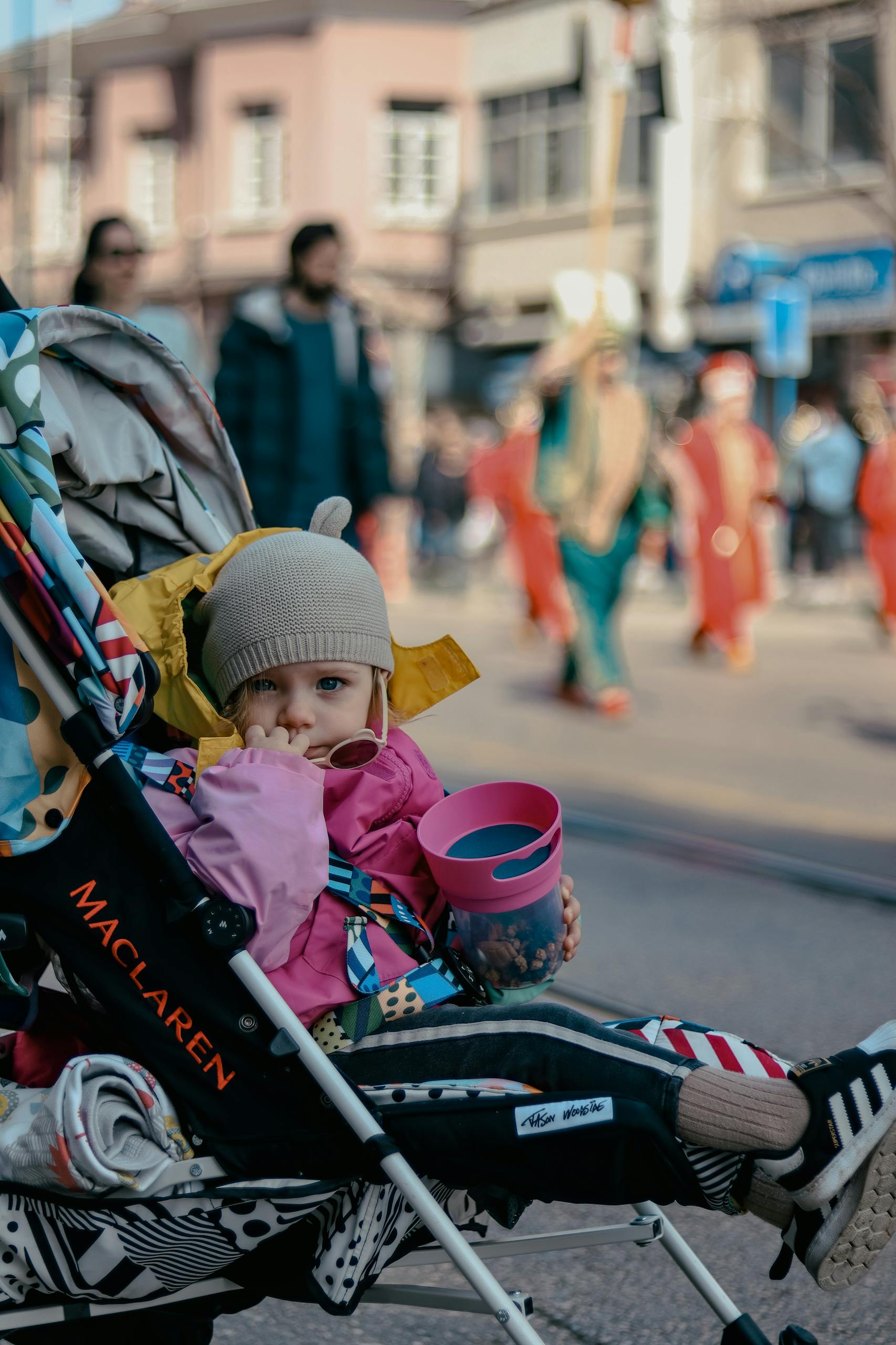 Parent pushing one of the best strollers for newborn to toddler with baby in a modern travel system stroller outdoors