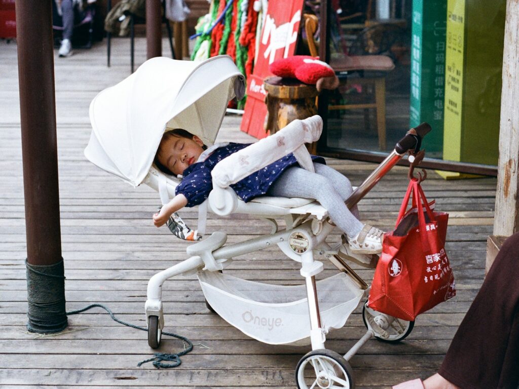 Baby sleeping comfortably in the best baby strollers for napping and a fully reclining stroller during a family walk outdoors.