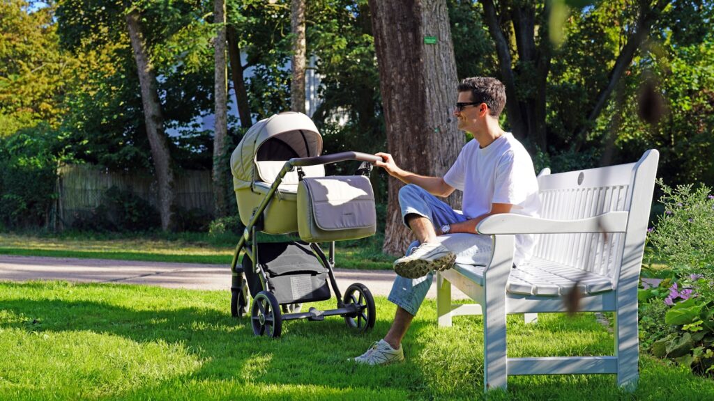 Baby sleeping comfortably in the best baby strollers for napping and a fully reclining stroller during a family walk outdoors.